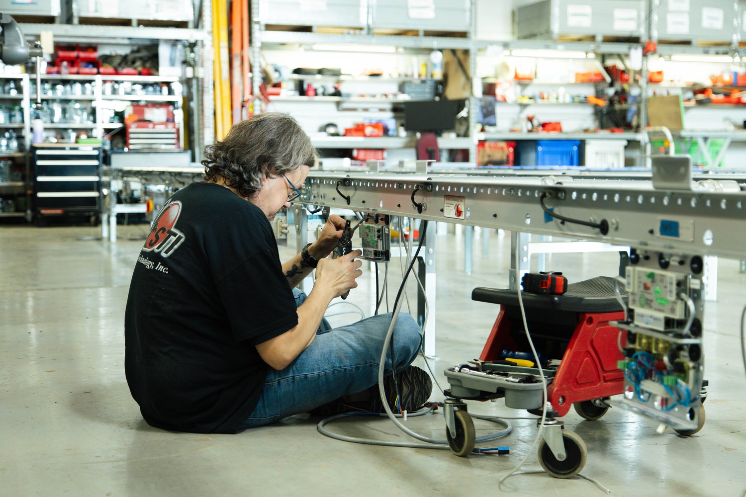 A technician assembling a curved blue-roller conveyor section