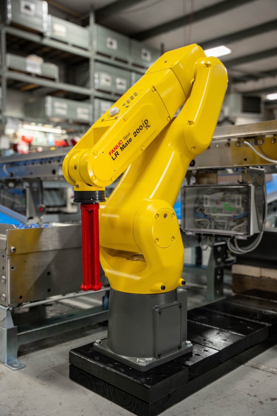 A FANUC industrial robot arm tending a conveyor